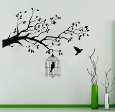 a bird in a cage hanging from a tree branch with birds flying around the branches