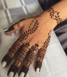 a woman's hand with henna tattoos on her left arm and hands, both decorated with leaves