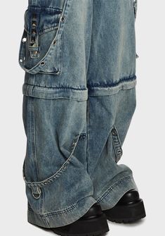 cuz conformity is the enemy of growth! These wide leg jeans have a washed denim construction, detachable grommet straps with clasp closures, front and back pockets, flap cargo leg pockets, pyramid studded detailing, a front zip-fly closure, and a convertible zip-off leg design so you can also wear them as shorts. Edgy Denim Cargo Style Jeans, Edgy Denim Jeans With Cargo Style, Edgy Cargo Jeans With Five Pockets, Utility Style Flare Jeans With Belt Loops For Streetwear, Alternative Style Wide Leg Denim Bottoms, Alternative Wide Leg Denim Bottoms, Punk Style Denim Cargo Jeans For Streetwear, Edgy Denim Blue Cargo Jeans With Pockets, Edgy Denim Cargo Jeans With Belt Loops