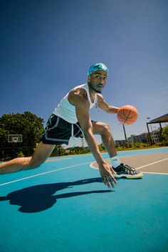 a man in white shirt and black shorts playing with a basketball on a blue court