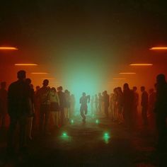 a group of people standing in a dark room with bright lights on the walls and floor