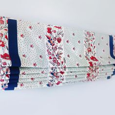 four pieces of blue and white fabric with red flowers on them, hanging from the wall