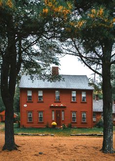 a red house surrounded by trees and grass