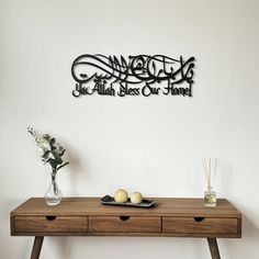 a wooden table with two vases on it and a metal wall art above it