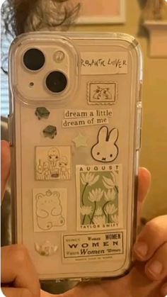 someone is holding up their phone case with stickers on it and there are other things in the back