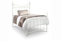 a white metal bed with two pillows on it