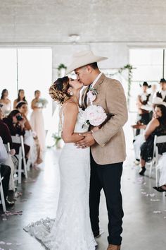 a bride and groom kiss as they walk down the aisle at their wedding ceremony in front of an audience