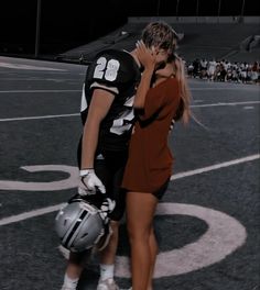 a man and woman are kissing on the football field