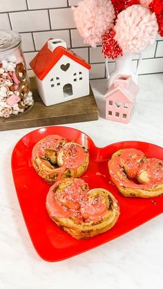 some donuts are sitting on a red heart shaped plate