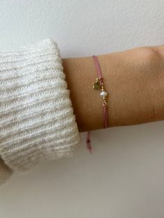 This silk cord bracelet is a fresh take on a friendship bracelet. It is made with high quality materials. You can choose the cord colour, the gemstone and charm of your choice. D E T A I L S  *It features a small  AA quality gemstone/pearl in between seamless gold filled beads and a tiny 18k gold filled charm. Charm measures between 5.5 mm and 6mm and is free moving *The cord is natural silk cord that has been twisted for strength and doubled over. Cord measures 0.6mm. *Choose the cord colour you prefer from the drop down menu. *If the silk should arrive kinked it will straighten itself out after a few hours after coming into contact with your skin. *You can expect the ends to flare creating a pretty tassel. *Bracelet is adjustable just move the slider bead up and down. *It comes with a cr Pink Nylon Cord Bracelets As Gift, Pink Nylon Cord Bracelet As A Gift, Nylon Cord Bracelet, Silk Cord Bracelet, Bracelet Pearl, Bracelet Friendship, Beads Bracelet Design, Tassel Bracelet, Bracelet Gemstone