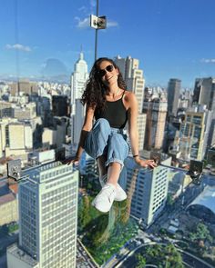 a woman hanging from the side of a tall building with her legs in the air