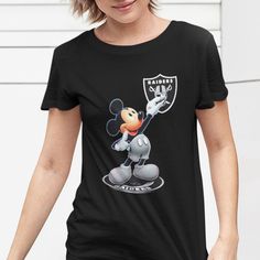 a woman wearing a black shirt with mickey mouse on it's chest and holding a football