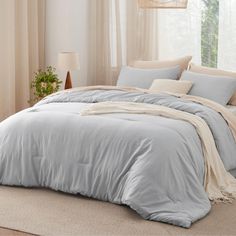 a bed with blue comforters and pillows in a room next to a large window