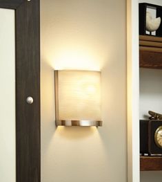 a wall light that is mounted on the side of a wall next to a book shelf