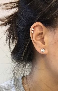 a close up of a person with ear piercings on their ears and behind them is a white wall