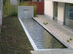 an outdoor water feature in the middle of a garden with gravel and grass around it