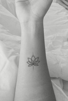 a black and white photo of a woman's arm with a lotus tattoo on it