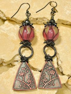 the earrings are decorated with pink and silver glass beads, hanging from black metal hooks