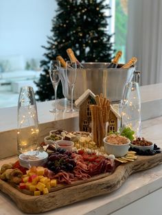 a platter with wine glasses, crackers, cheese and meats in front of a christmas tree