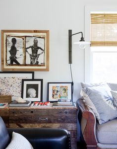 a living room filled with furniture and framed pictures on the wall above a table next to a window