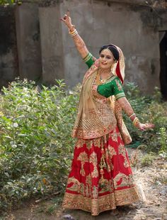 a woman in a red and green outfit dancing on the ground with her arms outstretched