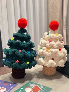 two crocheted christmas trees sitting on top of a table next to each other