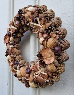 a wreath made out of pine cones and acorns hangs on the front door