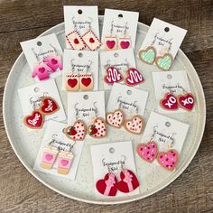 a white plate topped with lots of valentine's day cookies and heart shaped earrings