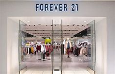 a store front with the words forever 21 on it's glass door and clothes in display