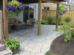 an outdoor patio with seating and flowers in the center, next to a wooden pergoline