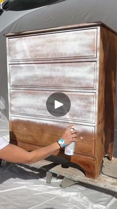 a woman is painting an old dresser with white paint on the outside and wood in the inside