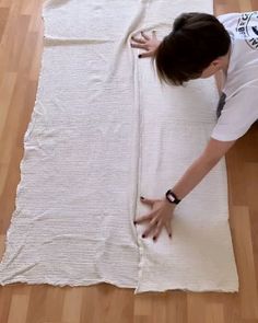 a woman laying on top of a white rug with her hands in the air next to it