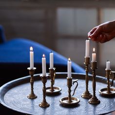 a person lighting candles on top of a metal tray with several smaller ones in the middle