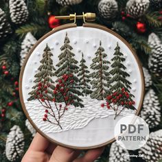 a hand embroidered christmas scene with pine trees and berries