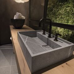 a large concrete sink sitting on top of a wooden counter next to a light fixture