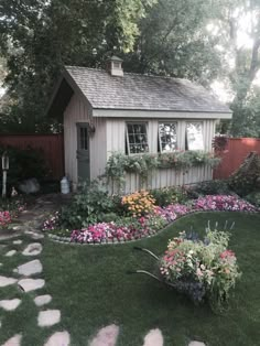 a small garden shed with flowers in the front yard and walkway leading up to it