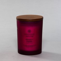 a pink candle with a wooden lid on a white surface