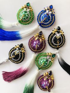 six pairs of beaded earrings with tassels and beads in different colors on a white surface