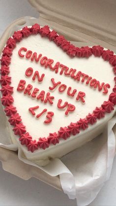 a heart shaped cake with writing on it in a cardboard box that says congratulationss on your break up