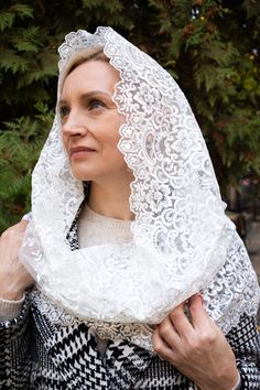 a woman wearing a white shawl and black and white checkered coat with lace on it