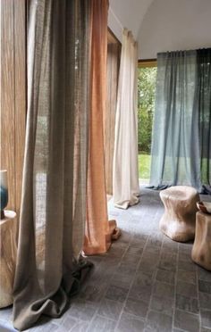 an open room with sheer curtains and wooden stools