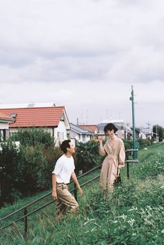 two people walking up some stairs in the grass and one is talking to another person