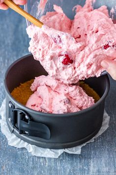 someone is scooping ice cream into a black bowl with cranberries on top