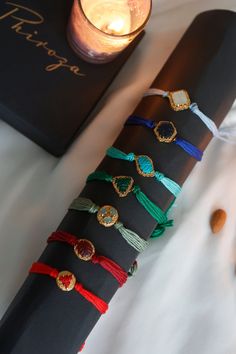 a stack of bracelets sitting on top of a table next to a candle and book