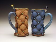 two ceramic mugs with handles made to look like they are wrapped in blue and green yarn