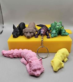 four different colored plastic animals sitting on a yellow box with a keychain attached to it