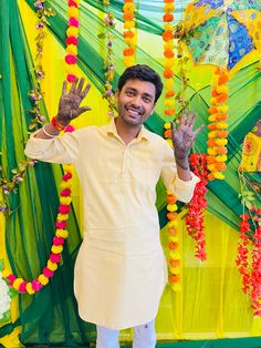 a man standing in front of a colorful backdrop with flowers and garlands on it