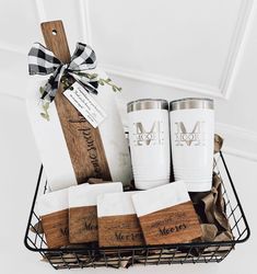 a basket filled with personalized coffee mugs and napkins next to a wooden cutting board