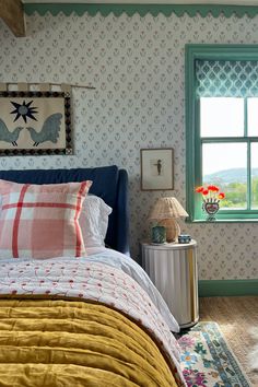 a bed sitting next to a window with a blue headboard and yellow comforter