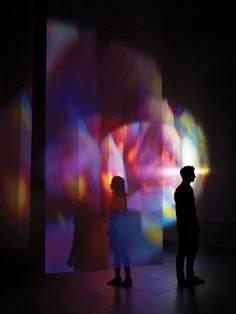 two people standing in front of a colorful light